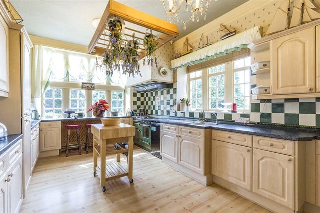 The charming country-style kitchen boasts fitted cabinets, a double oven, integrated appliances, breakfast bar and a small island at its centre.