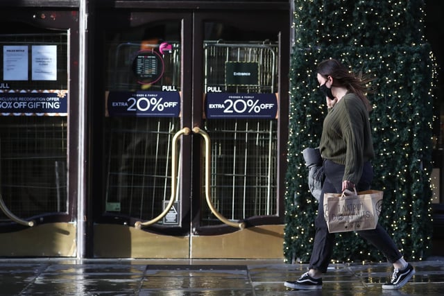 A woman walks past the closed House of Fraser store on Buchanan Street in Glasgow on the first day after eleven local council areas in Scotland moved into Level 4 restrictions to slow the spread of coronavirus.