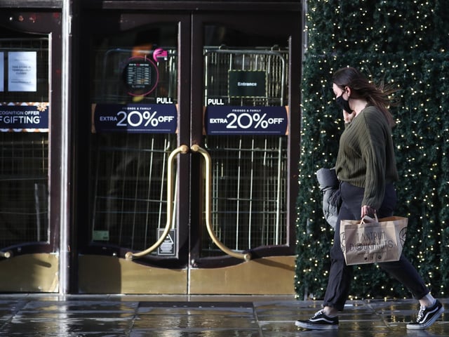 A woman walks past the closed House of Fraser store on Buchanan Street in Glasgow on the first day after eleven local council areas in Scotland moved into Level 4 restrictions to slow the spread of coronavirus.