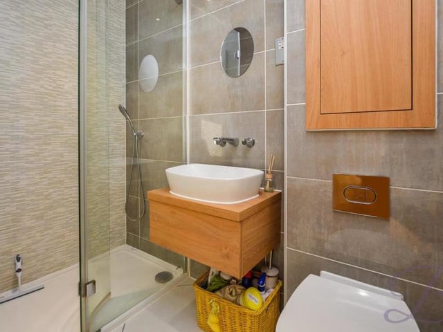The attractive en suite to the master bedroom features a walk-in shower with digital thermostat. It is also blessed with full-height, contemporary tiling, a wall-hung basin, vanity unit, chrome fixtures and a low-flush WC.