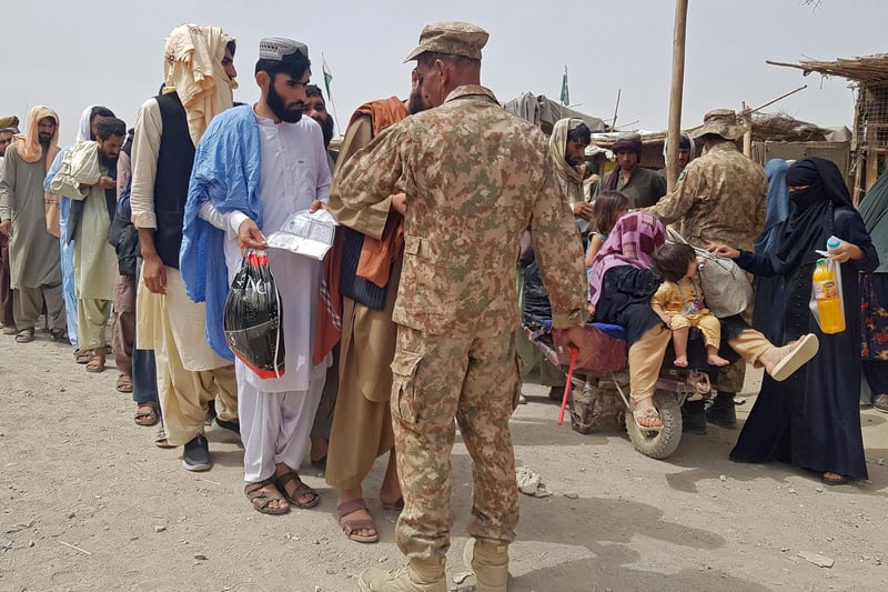 Pakistan's soldiers check the documents of stranded Afghan nationals wanting to return to Afghanistan at the Pakistan-Afghanistan border crossing point in Chaman