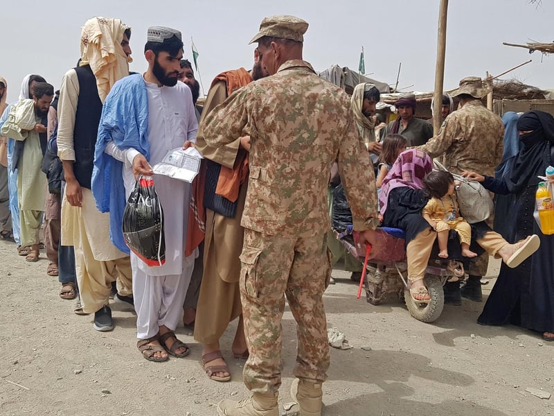 Pakistan's soldiers check the documents of stranded Afghan nationals wanting to return to Afghanistan at the Pakistan-Afghanistan border crossing point in Chaman
