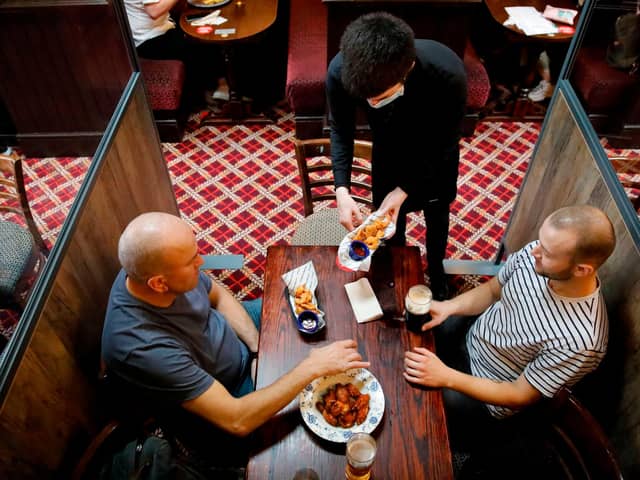 Customers are pictured being served a meal at a Wetherspoon pub. The chain has launched a deal called Stay Out to Help Out. Picture: Tolga Akmen/AFP via Getty Images.