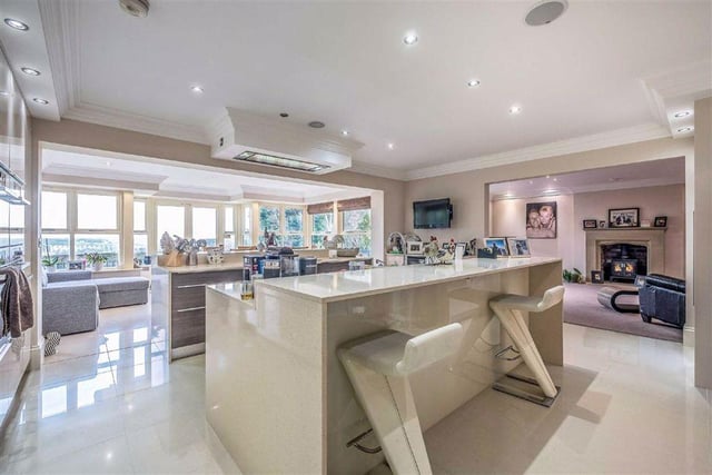 The open plan kitchen is modern in design, with fitted cupboards and integrated appliances, a breakfast island at its centre and a space for dining in front of the French doors, with views over the garden.