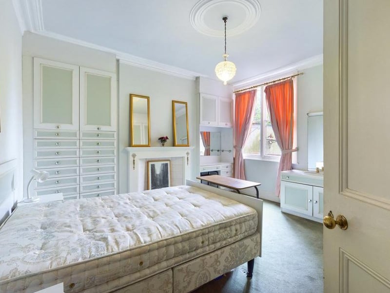 Lounge - Currently in use as a ground floor bedroom - Timber framed single glazed window to the rear elevation, ceiling coving, a range of fitted wardrobes and draws to two walls, inset wash basin with vanity surround, feature fire surround with tiled inset; power point.