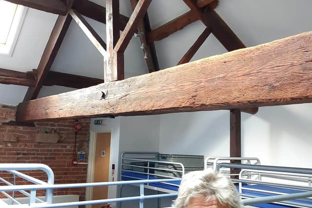 Committee member Ann Evans in a dormitory with old roof timbers exposed.