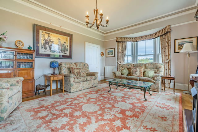 A comfortable sitting room features a large bay window with spectacular views and an ornate fireplace with electric fire.