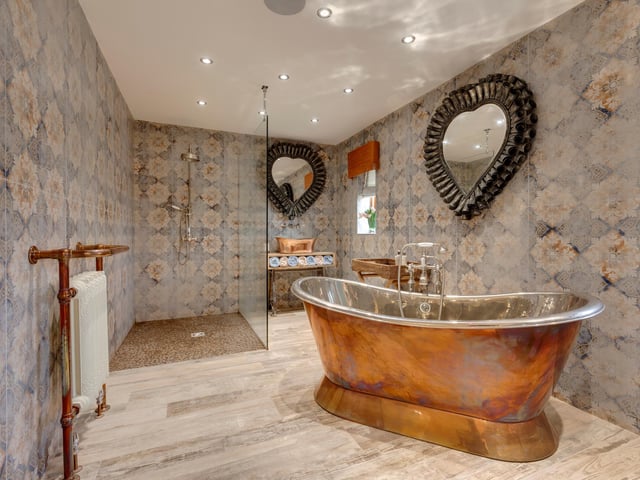 There are eight bathrooms located throughout the property, with this en-suite featuring a freestanding Hurlingham copper bath, a double width walk-in shower and built-in speakers.