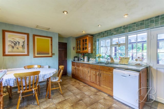 Another view of the kitchen, which has a large window overlooking the garden. An inset sink and drainer has a mixer tap above, while the floor is tiled.