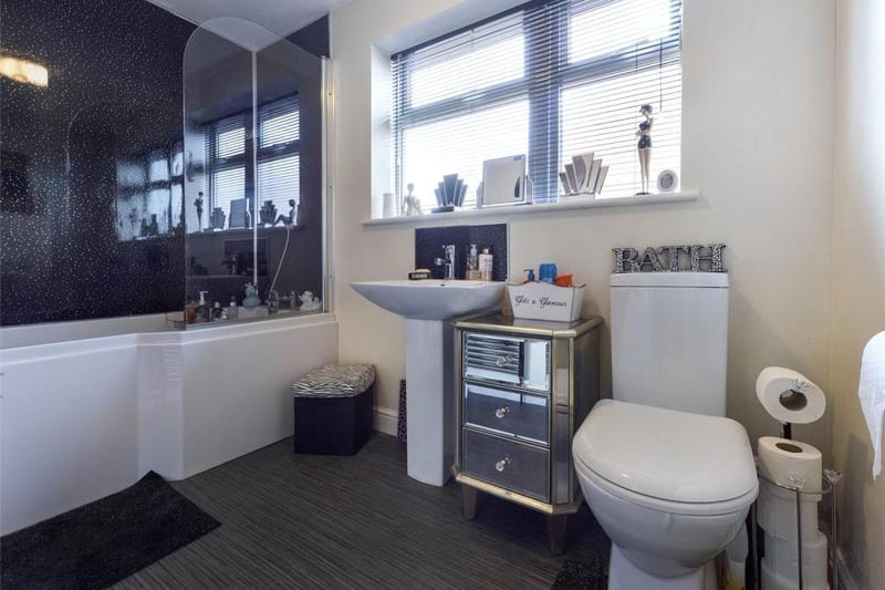 Family bathroom - Modern white suite comprising low level WC, pedestal wash basin and panelled shower bath with shower head mixer tap, fitted shower screen and wall panelling. uPVC double glazed window to the side elevation, towel radiator.