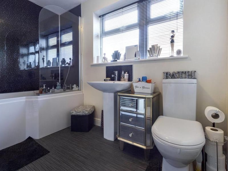 Family bathroom - Modern white suite comprising low level WC, pedestal wash basin and panelled shower bath with shower head mixer tap, fitted shower screen and wall panelling. uPVC double glazed window to the side elevation, towel radiator.
