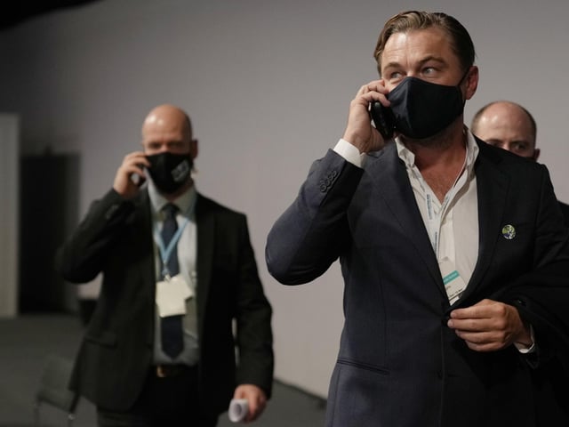 The U.S. actor spoke on a mobile phone as he walked through the corridor during the COP26 U.N. Climate Summit.
