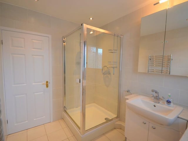 Family shower room - An attractively presented shower incorporating a large shower enclosure with mains fed shower and glass panels, a vanity unit with cupboards and inset wash basin, low level flush wc, chrome heated towel rail, extractor fan, inset down lighting, UPVC double glazed obscure window and complimented with stylish ceramic wall and floor tiles.