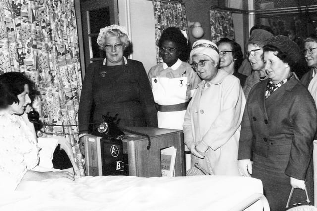 Mrs Winifred Hart, a patient for six weeks, is the first to use the telephone trolley presented to Lodge Moor Hospital, Sheffield, by Stannington Community Association.  The matron, Miss A Holder, and association members look on as Mrs Hartley calls her 10 year old grandaughter, Denise Bennett of Sharrard Road, Intake.