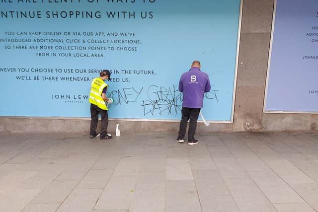 Graffiti is cleaned from an advertising board at John Lewis