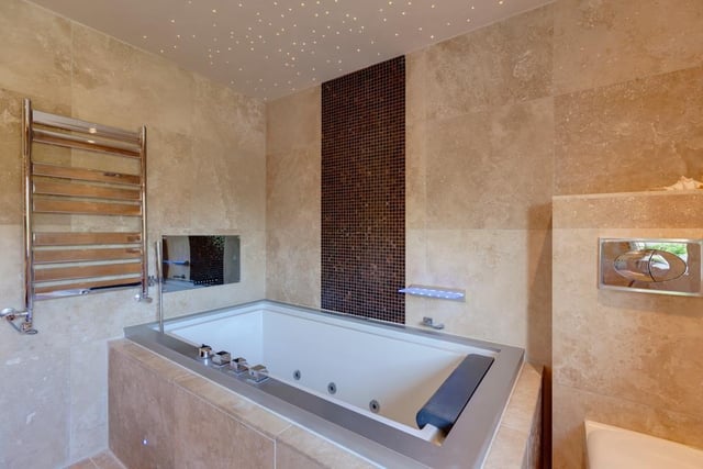 The family bathroom comprises his 'n' hers polished stone wash basins, an inset spa bath and recessed television, and a separate shower enclosure with a fitted rain head shower.