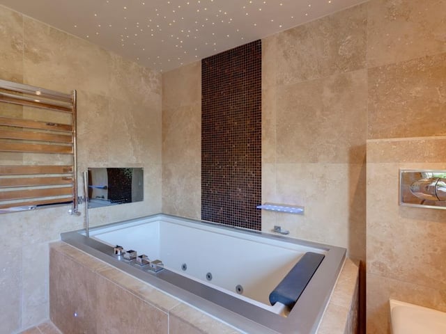 The family bathroom comprises his 'n' hers polished stone wash basins, an inset spa bath and recessed television, and a separate shower enclosure with a fitted rain head shower.