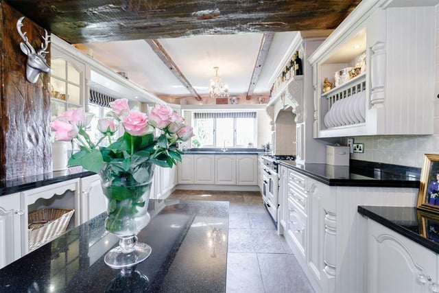 The kitchen is fitted with plate racks and glazed cabinets, inset spotlights, black granite work surfaces, a Rangemaster cooker and under-floor heating.