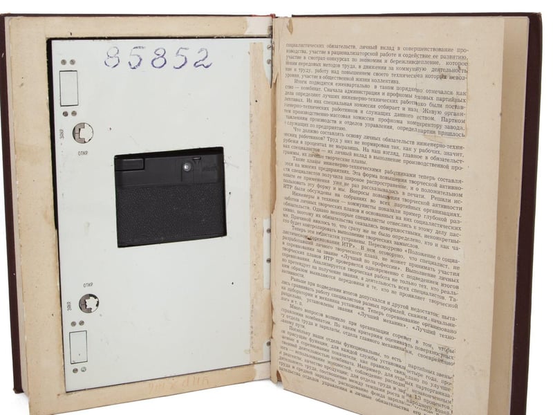 A Soviet KGB spy book containing a hidden "Neozit" camera, with the lens operating through a small moveable section on the front of the book. 9 3/4 by 6 5/8 by 2 inches Estimate: $2,000 - $3,000.