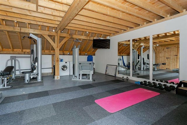 The home gym is generously sized with enough room for several pieces of equipment, and is also used as a storage area for a washing machine and dryer.