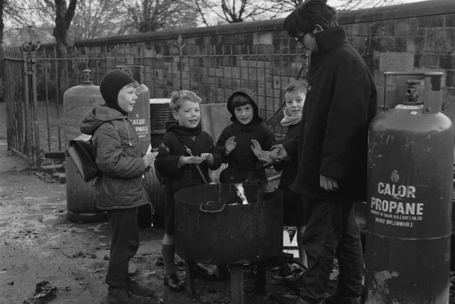 Four children warm themselves at a workman's propane brazier in Morningside Drive in November 1965.