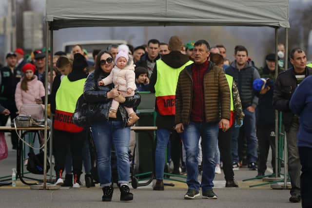 In this photo taken on Saturday, March 28, 2020, a crowd of football fans walk through a security gate to watch the Belarus Championship soccer match between Gorodeya and Shakhter in the town of Gorodeya, Belarus:  AP Photo/Sergei Grits