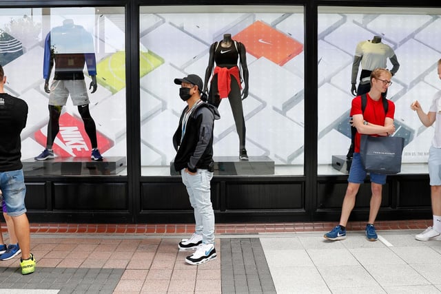 Shoppers, some wearing PPE (personal protective equipment), of a face mask or covering as a precautionary measure against COVID-19, queue to enter a recently re-opened Nike store at Gunwharf Quays.
