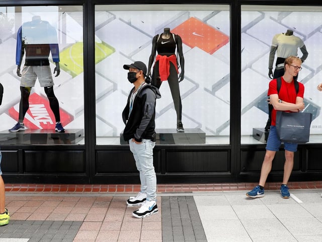 Shoppers, some wearing PPE (personal protective equipment), of a face mask or covering as a precautionary measure against COVID-19, queue to enter a recently re-opened Nike store at Gunwharf Quays.