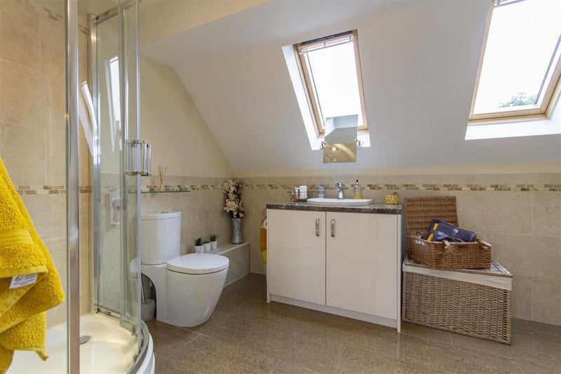The bathroom has two velux windows, a tiled floor and downlighting.