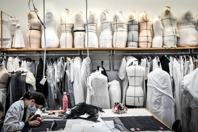 A seamstress works on a couture garment