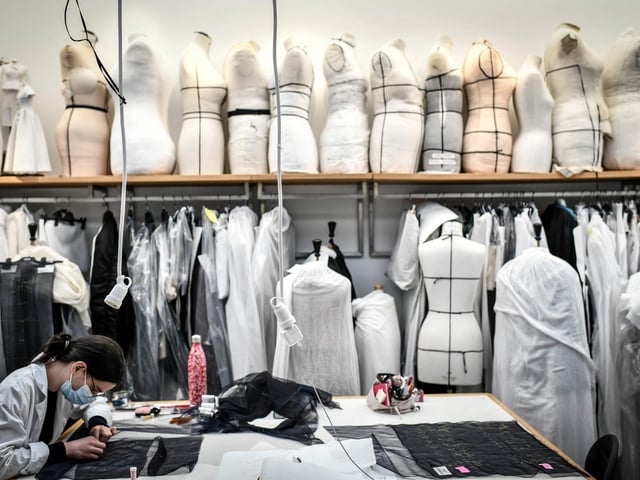 A seamstress works on a couture garment