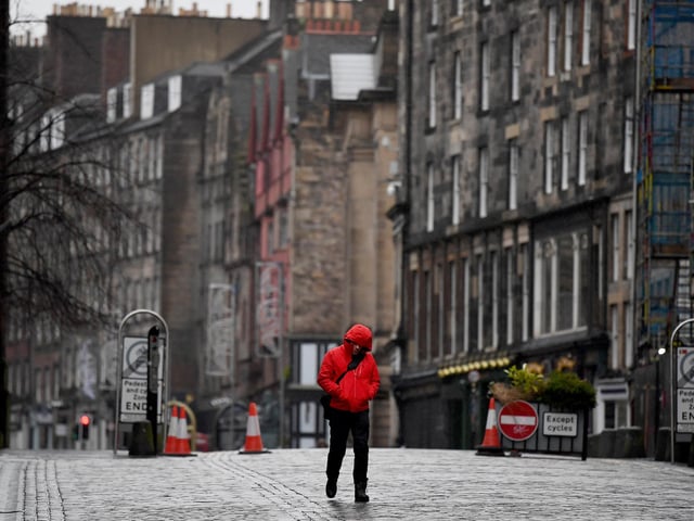 Members of the public walk through a deserted Edinburgh City Centre