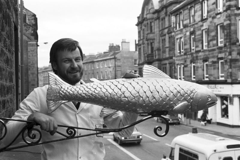 Owner Peter MacIntyre replaces the gilded salmon sign above Miller's fishmongers in Tollcross in November 1985.