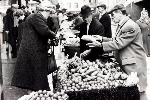 George Garrett and Matthew Clark (right) serve a customer from their fruit and vegetable stall in Dixon Lane, Sheffield, in November 1965