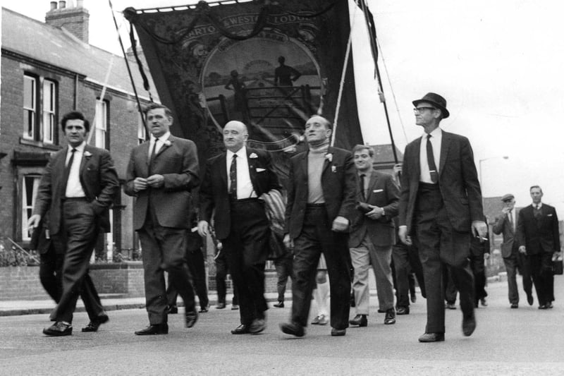 Led by Mr Paddy Cain, Harton and Westoe miners follow their band and banner through South Shields on their way to the Durham Miners Gala in 1969.