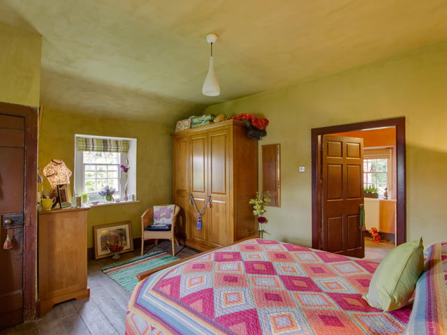 The cosy bedroom has rustic charm, with stripped wooden flooring and sash and case window
