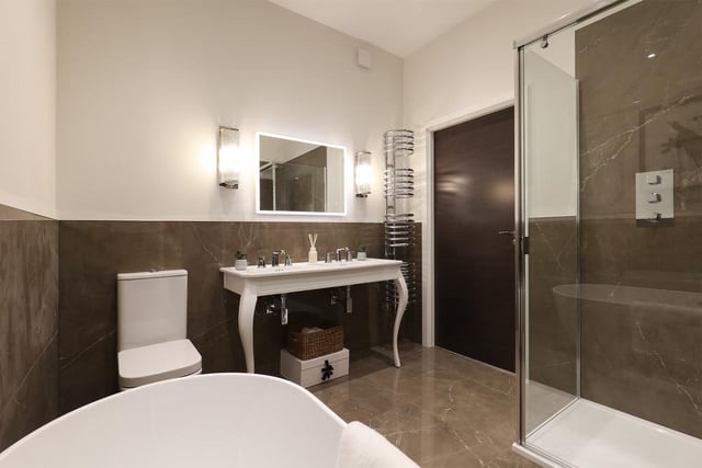 The en-suite to the main bedroom on the first floor combines a freestanding bath with Porcelanosa tiling.