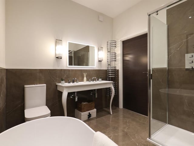 The en-suite to the main bedroom on the first floor combines a freestanding bath with Porcelanosa tiling.