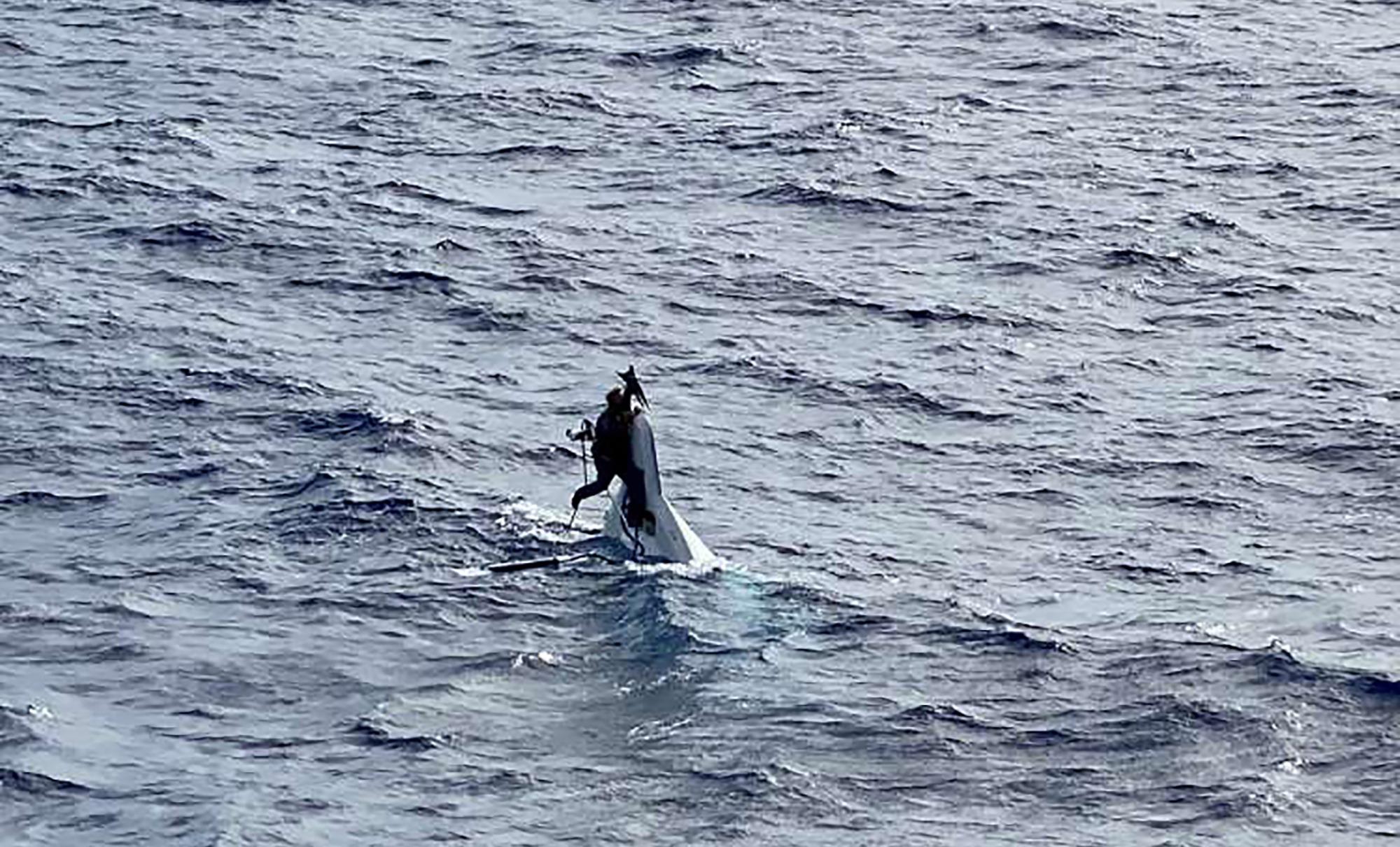 Stuart Bee, 62, clings to the hull of his 32-foot capsized recreational vessel