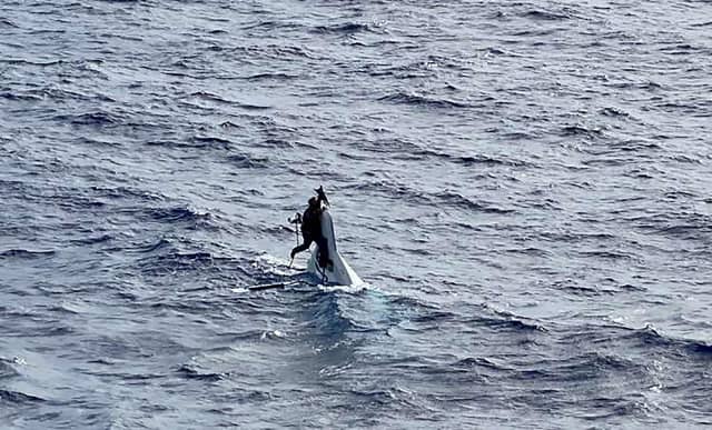Stuart Bee, 62, clings to the hull of his 32-foot capsized recreational vessel