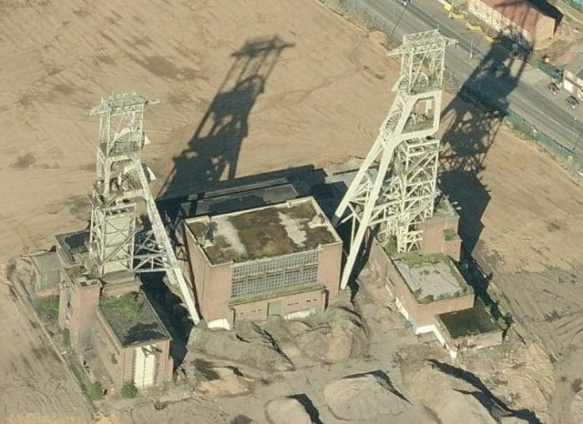 An aerial view of the headstocks showing the vegetation of the roof and many parts of the building covered with soil.
