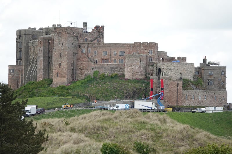 Production vehicles, lighting rigs, crane and huge banners at the entrance to Bamburgh Castle.