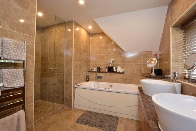 Four bathrooms are spread throughout the property, with this luxurious room benefiting from a large bath tub, walk-in shower cubicle, double sinks and marble tiling.