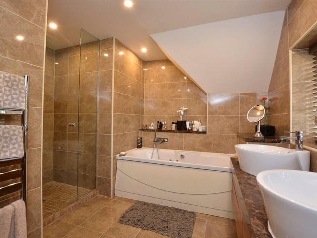 Four bathrooms are spread throughout the property, with this luxurious room benefiting from a large bath tub, walk-in shower cubicle, double sinks and marble tiling.