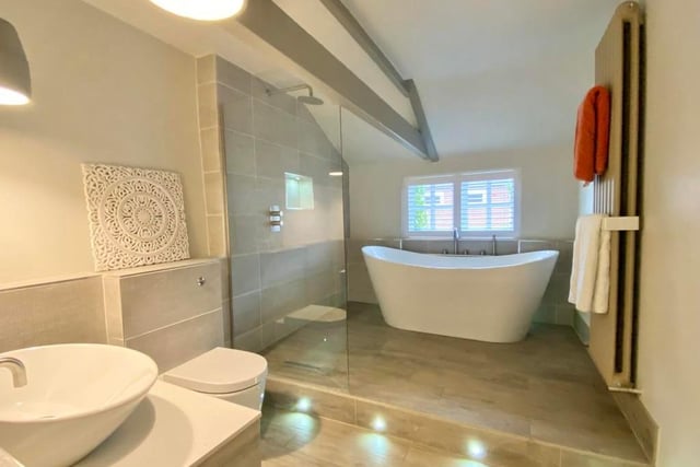 The main bathroom is modern and features not only a double-ended bath with centre tap and shower tap but also a drench shower-head with glass screen. It is topped by a vertical radiator, WC, wash basin with vanity storage beneath, beam ceiling and access to the home's loft.