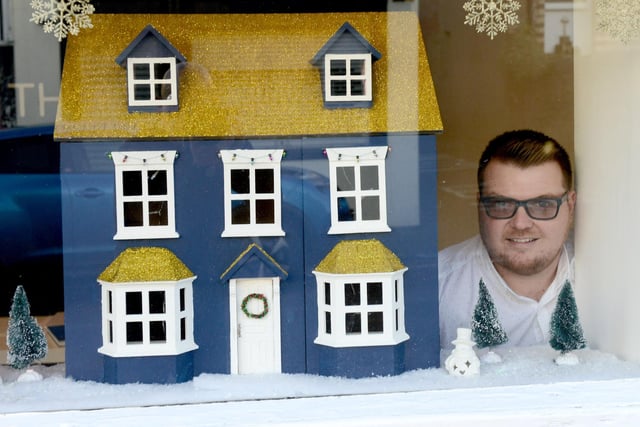Miles Thursby with the doll's house on display in the window of Miles Thursby Sales and Letting in Whitburn in 2019.