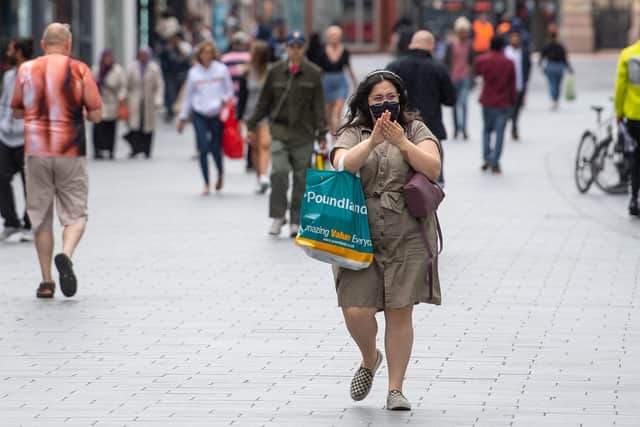 A woman sanitizes her hands as she walks through the city centre = Joe Giddens/PA Wire