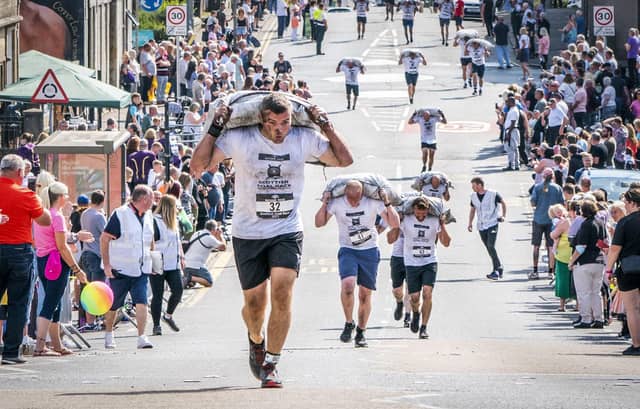 Competitors take part in the Scottish Coal Carrying Championships through the streets of Kelty in Fife. Picture date: Saturday August 28, 2021. PA Photo. The annual event is one of only two Coal Races in the world and the men's race requires participants to carry a 50-kilo bag of coal and the women's race requires a 25-kilo bag of coal to be carried over 1000 metres through the village. Photo credit should read: Jane Barlow/PA Wire
