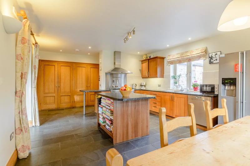 The spacious kitchen/dining room is fitted with a range of stylish units, a central island, a stainless steel range cooker and a Miele dishwasher.