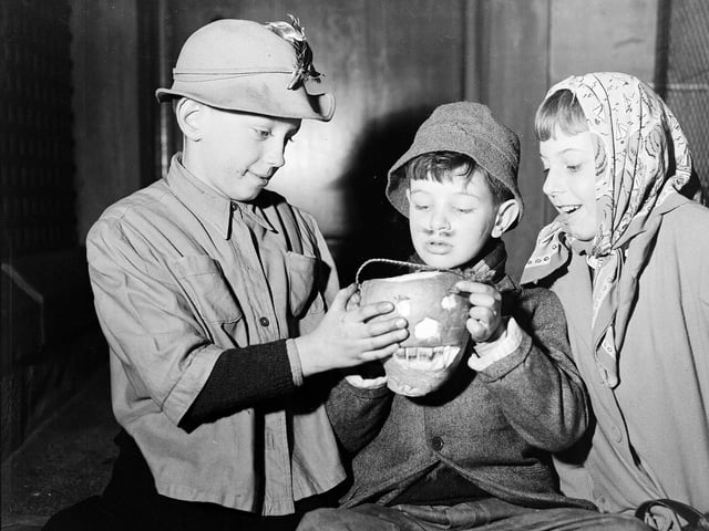 Young Edinburgh guisers warm their hands over their turnip lanterns at Halloween.